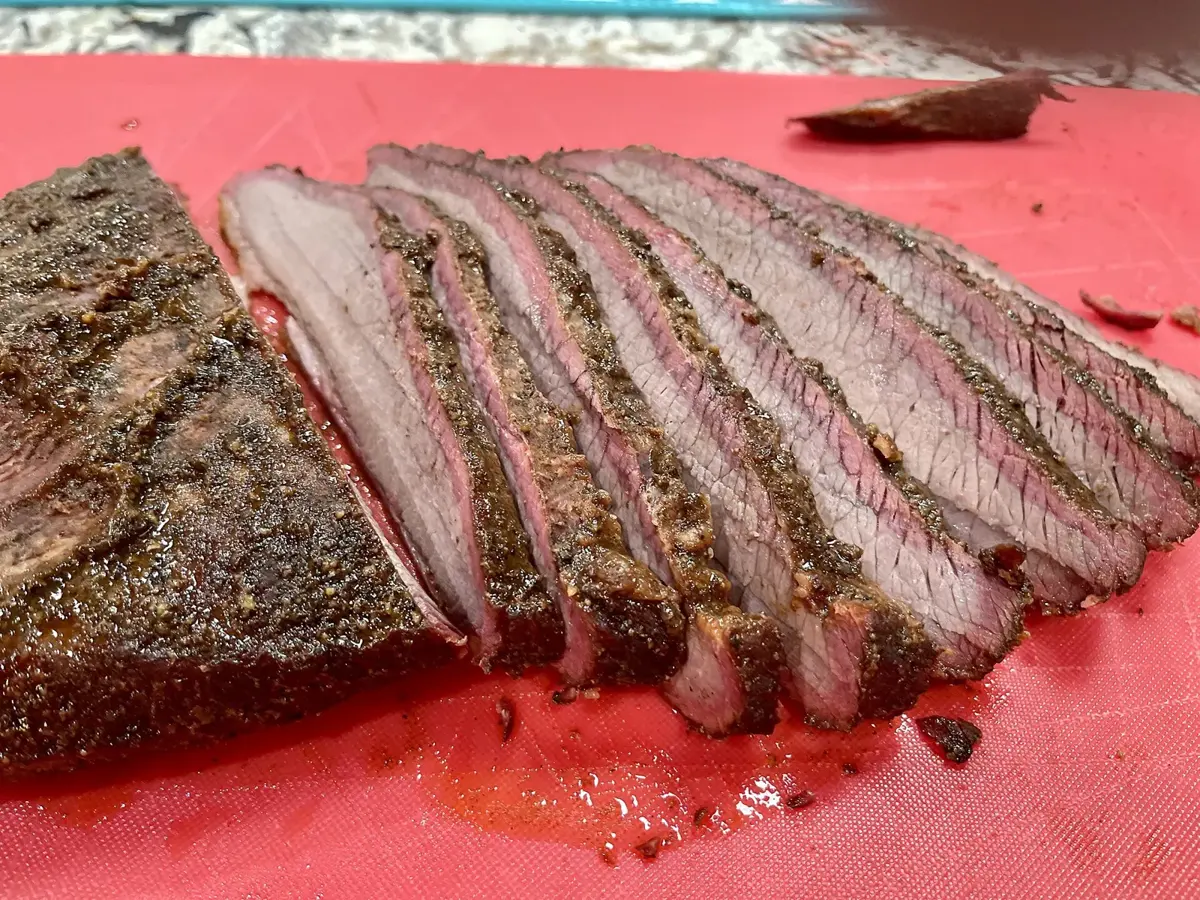 Sliced smoked brisket showing a pink smoke ring and dark bark
